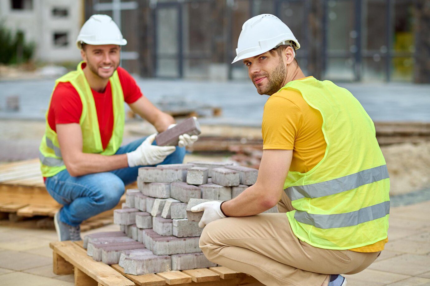 Two workers stacking bricks looking at camera<br />
